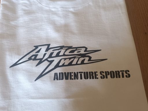 T-Shirt Honda Africa Twin XRV750 Weißes T-Shirt mit dem Aufdruck "Africa Twin Adventure Sports" in stylisierter Schrift.