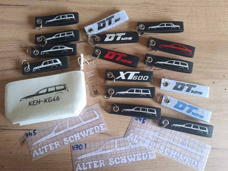 Keychain und Bierdeckel Verschiedene Aufnäher und Aufkleber mit Fahrzeugmotiven in schwarz, rot und weiß.