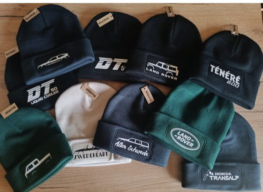 Holzbike Beanie Zehn verschiedene Mützen in grünen, weißen und blauen Farbtönen mit Logos.