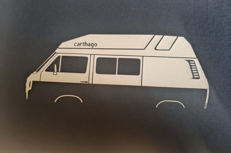 Sonderarbeiten und Einzelstücke Silhouette eines Campingbusses in Schwarz und Weiß auf dunklem Hintergrund.