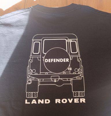 T-Shirt Defender Heckansicht Schwarzes T-Shirt mit weißem Druck eines Land Rover Defender im Rückansicht.
